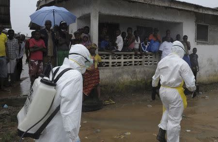 Health workers wearing protective clothing prepare to carry an abandoned dead body presenting with Ebola symptoms at Duwala market in Monrovia August 17, 2014. REUTERS/2Tango