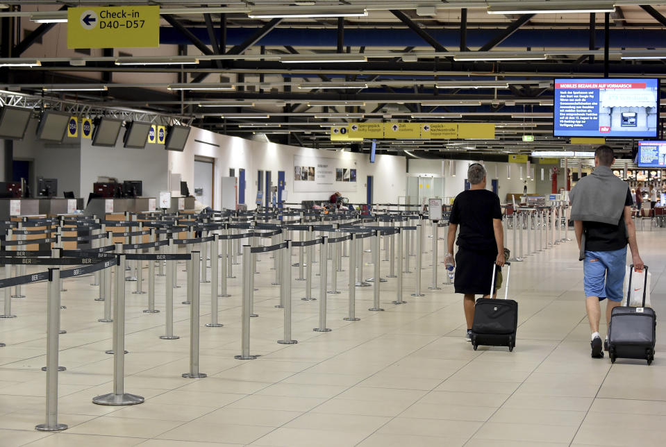 Passenger walk through the empty departure hall of the Schoenefeld airport near Berlin Friday, Aug. 10, 2018 when several flights of Irish Ryanair airline had been cancelled due to a strike of pilots. (Bernd Settnik/dpa via AP)