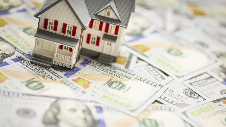 Small model home on top of a pile of cash