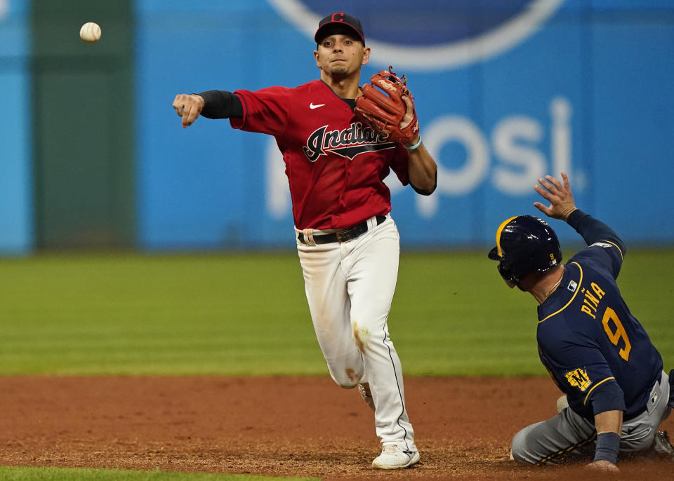 Cleveland Indians' Andres Gimenez, left, gets Milwaukee Brewers' Manny Piña out at second base in the eighth inning of a baseball game, Friday, Sept. 10, 2021, in Cleveland. Daniel Vogelbach was out at first base for a double play. (AP Photo/Tony Dejak)