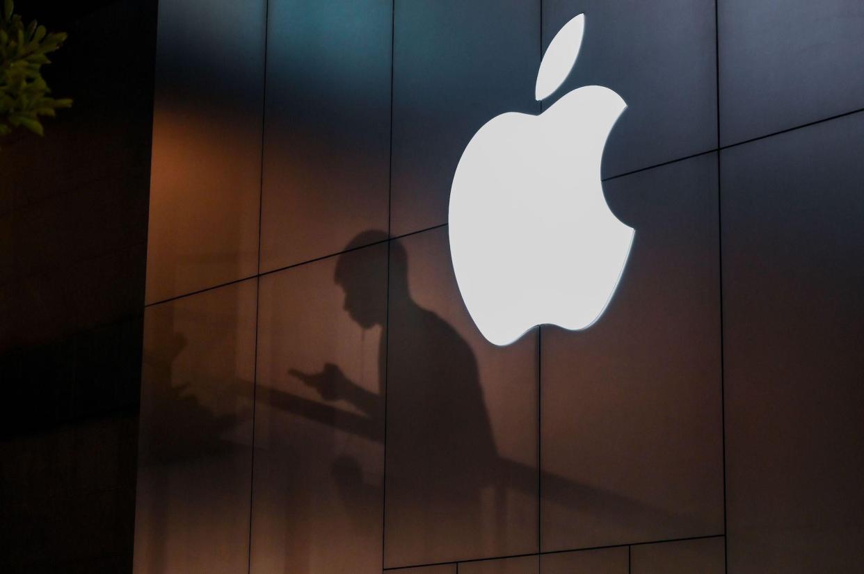 The shadow of a man is cast on the wall of an Apple store as he uses his mobile phone in Beijing on August 26, 2019: GREG BAKER/AFP via Getty Images