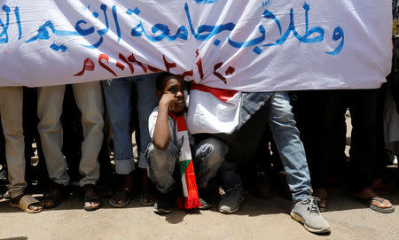 A boy sits on the gorund as a group of protesters stage a protest in front of the Defence Ministry in Khartoum, Sudan, April 20, 2019. REUTERS/Umit Bektas