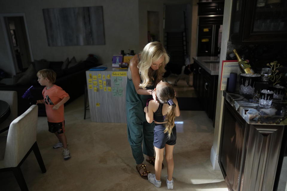 Florida state Sen. Lauren Book kisses her six-year-old daughter Kennedy Byrnes as twin brother Hudson Byrnes walks nearby, Oct. 24, 2023, at their home in Plantation, Fla. Book uses a phone app which provides real-time rocket alerts to Israeli citizens to stay informed and help her children what is happening in Israel. "I don't want to forget. I don't want my children to ever forget. I don't want my community to forget." (AP Photo/Rebecca Blackwell)