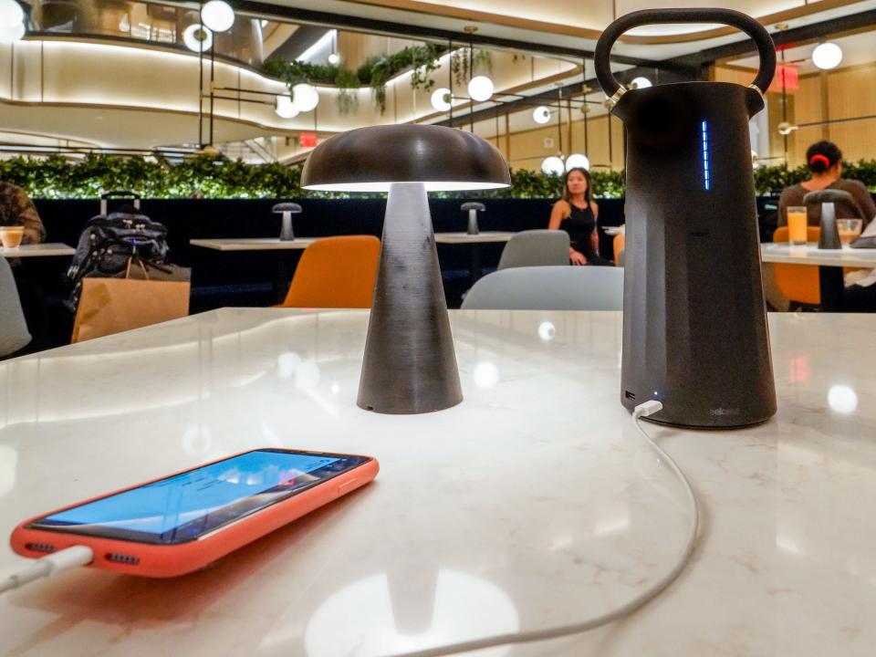 A phone plugged into a large, black charging battery on a white table