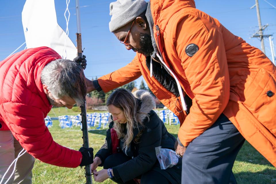 Brian Fishman, 55, executive director of Temple Shir Shalom in West Bloomfield Township, left, works with Stacy Cohen, and Ron Spencer, both with the Jewish Federation of Detroit to anchor a 30 foot banner on Wednesday, Nov. 1, 2023 on the lawn of the Temple Shir Shalom. The banner commemorates the hostages taken by Hamas and demands they be released.