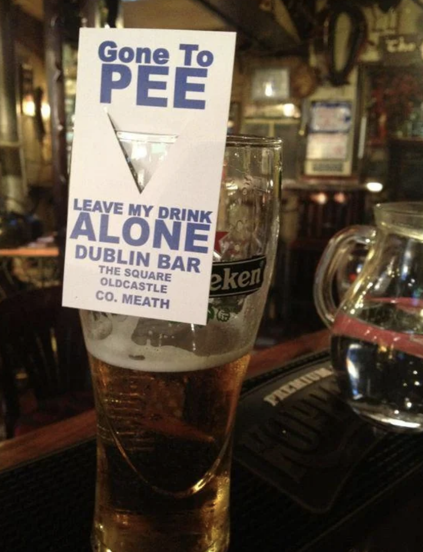 Sign on a glass of beer reads "Gone to PEE - Leave my drink alone" at The Square Castle bar