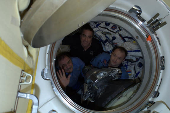 The Expedition 36 crew of the International Space Station waves farewell before undocking a Soyuz space capsule to return to Earth on Sept. 10, 2013. They are Russian cosmonauts Alexander Misurkin (right), Pavel Vinogradov (left) and NASA astro