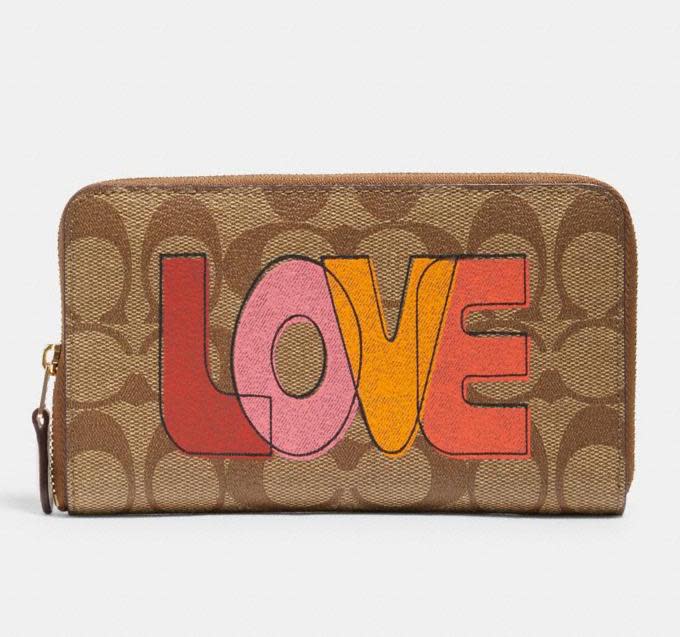 Medium Id Zip Wallet In Signature Canvas With Love Print. Image via Coach Outlet.