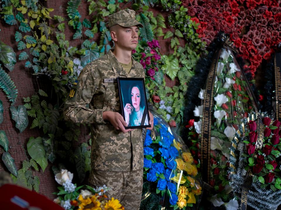 A Ukrainian soldier holds a photo of Olga Simonova (AP)