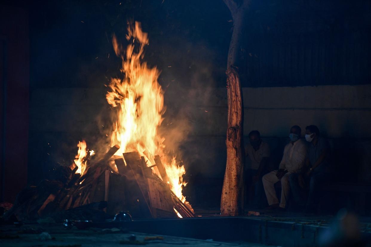 Relatives watch the cremation of their loved one who died of the Covid-19 coronavirus at Nigambodh Ghat Crematorium in New Delhi on April 28, 2021.