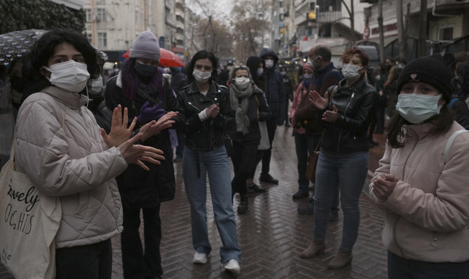 Women wearing masks to protect against the spread of coronavirus, stand in the rain during a women's right protest, in Ankara, Turkey, Saturday, March 20, 2021. Turkey's weekly geographic COVID-19 figures keep increasing according to Health ministry statistics released late Saturday as the country continues its "controlled normalization." (AP Photo/Burhan Ozbilici)