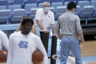 North Carolina trainer Doug Halverson, center, stands by while players warm up prior to an NCAA college basketball game against Syracuse in Chapel Hill, N.C., Tuesday, Jan. 12, 2021. The coronavirus pandemic has added another constantly shifting layer to what they do. The last 10 months have turned into a complicated juggling act of tending to athletes' day-to-day needs while dealing with the intricacies that come with trying to play sports and keeping everyone safe — themselves included — in a pandemic. (AP Photo/Gerry Broome)