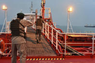 In this Sunday, July 21, 2019 photo, two armed members of Iran's Revolutionary Guard inspect the British-flagged oil tanker Stena Impero, which was seized in the Strait of Hormuz on Friday by the Guard, in the Iranian port of Bandar Abbas. Global stock markets were subdued Monday while the price of oil climbed as tensions in the Persian Gulf escalated after Iran's seizure of a British oil tanker on Friday. (Morteza Akhoondi/Mehr News Agency via AP)