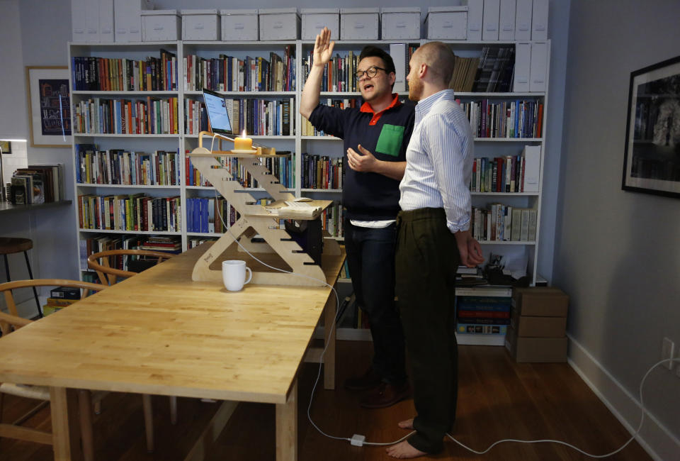 Casper ter Kuile, left, and his husband, Sean Lair, teach the song "Hinei Ma Tov" to a virtual community choir from their living room in the Brooklyn borough of New York on Sunday, March 29, 2020. Created to combat social isolation in times of coronavirus, more than one hundred people from around the world joined the hour-long sing along session. (AP Photo/Jessie Wardarski)