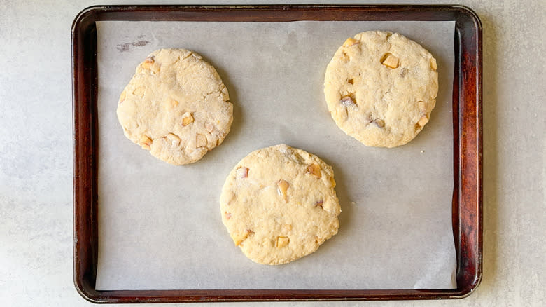 Peaches and cream scone dough disks on parchment on baking sheet