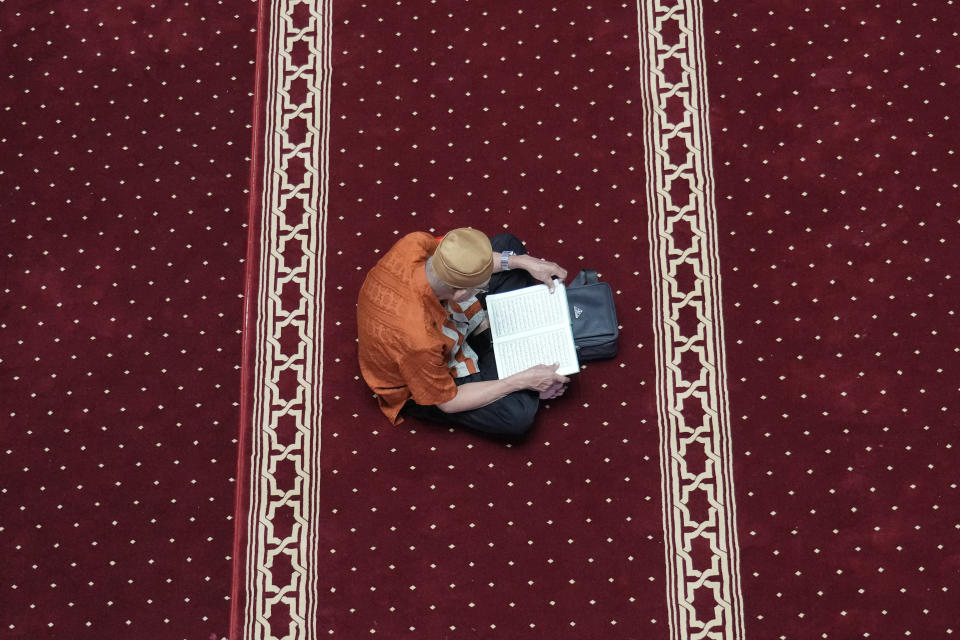 A Muslim reads the Quran while waiting for the time break his fast during the first day of Ramadan at the Istiqlal Mosque in Jakarta, Indonesia, Tuesday, March 12, 2024. (AP Photo/Achmad Ibrahim)