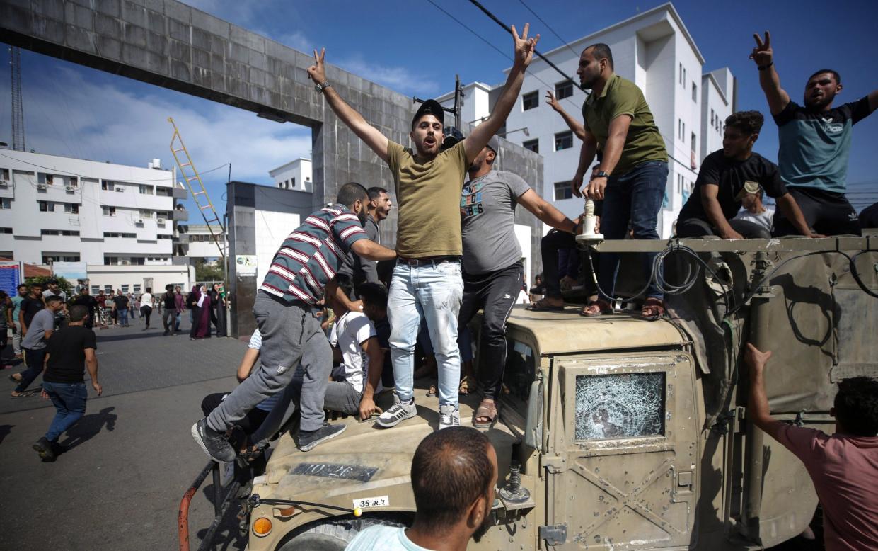Palestinians ride an Israeli military jeep in the streets of Gaza during the storming of Israeli settlements
