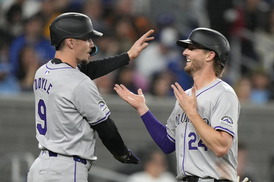 Colorado Rockies' Brenton Doyle (9) and Ryan McMahon (24) celebrate after scoring on a hit by teammate Kris Bryant during fourth-inning baseball game action against the Toronto Blue Jays in Toronto, Friday, April 12, 2024. (Frank Gunn/The Canadian Press via AP)