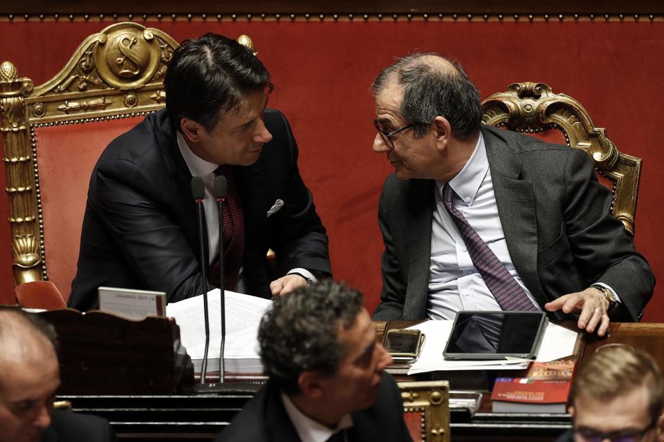 In this picture taken Saturday, Dec. 22, 2018, Italian Prime Minister Giuseppe Conte, left, talks to Italian Economy Minister Giovanni Tria prior to the start of a confidence vote on the budget law at the Italian Senate in Rome. (Riccardo Antimiani/ANSA Via AP)