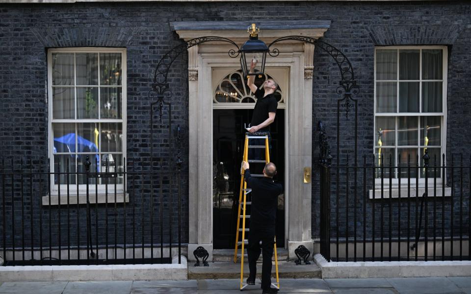 Workers at 10 Downing Street are making the most of a quiet day as they change the light outisde the most famous residence in the country