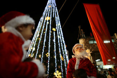 FILE PHOTO: Boys wearing Santa Claus costumes are carried during a Christmas tree lighting ceremony in the northern town of Nazareth, the town of Jesus' boyhood, December 12, 2012. REUTERS/Ammar Awad/File Photo