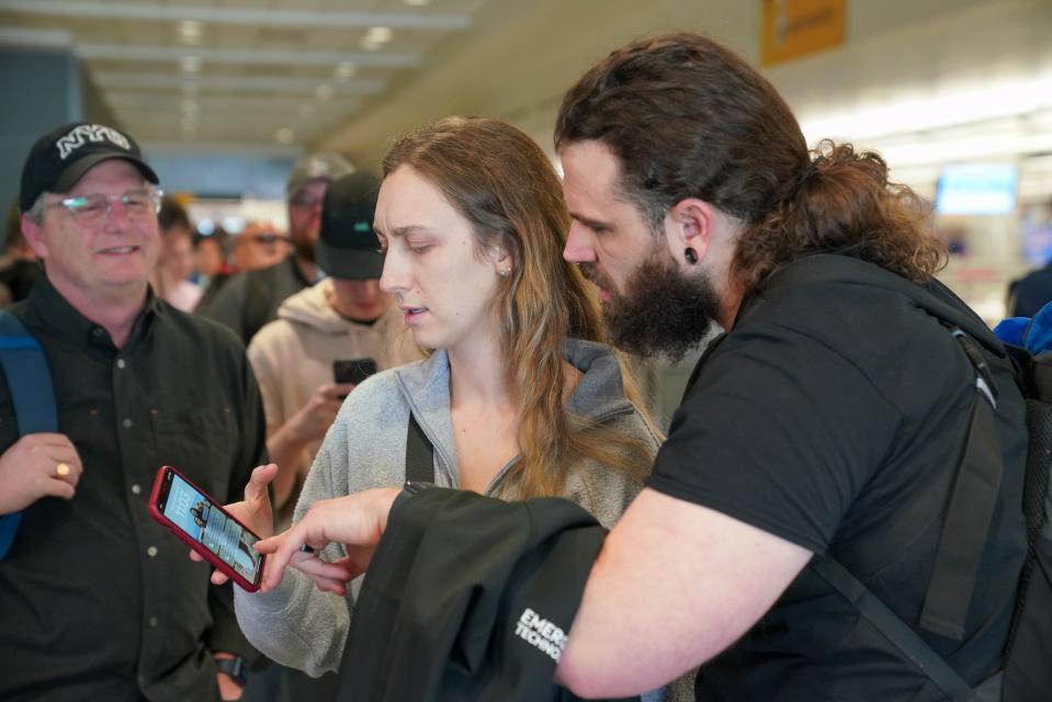 Kassie Novakovich and her husband, Ryan Williams, check her phone to see a message from Southwest telling them their flight to Cozumel, Mexico, was scheduled to depart at 7 a.m., although it was 11 a.m. and the flight had already been canceled at Denver International Airport on Tuesday, Dec. 27, 2022.