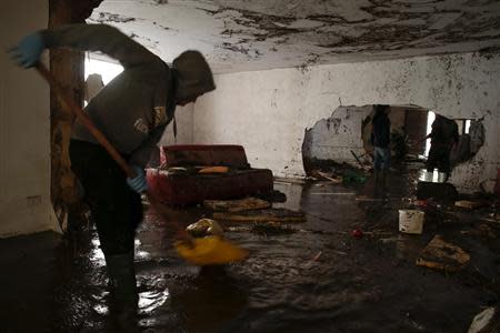 A man sweeps muddy water out of a flooded home after extreme rainfall due to Cyclone Cleopatra in Olbia on Sardinia island November 20, 2013. REUTERS/Tony Gentile