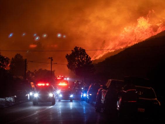 Firefighters and media flee from the flames of the Lake Fire in Lake Hughes, California, 12 August (EPA)