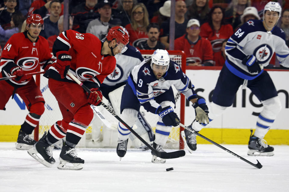 Carolina Hurricanes' Michael Bunting (58) controls the puck as Winnipeg Jets' Alex Iafallo (9) looks on during the third period of an NHL hockey game in Raleigh, N.C., Saturday, March 2, 2024. (AP Photo/Karl B DeBlaker)
