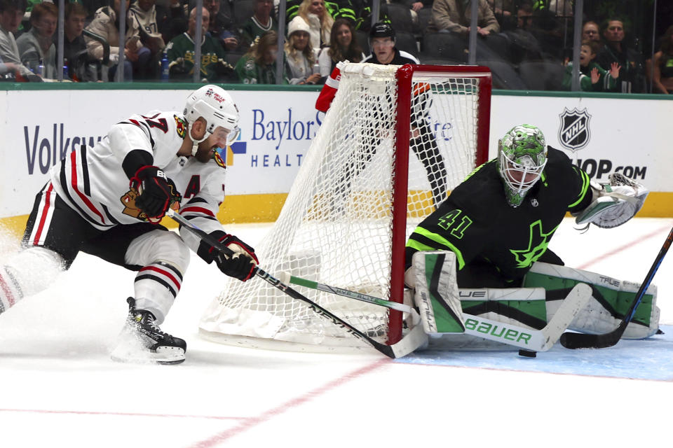 Chicago Blackhawks left wing Nick Foligno (17) takes a shot from behind the goal as Dallas Stars goaltender Scott Wedgewood (41) defends in the second period of an NHL hockey game, Sunday, Dec. 31, 2023, in Dallas. (AP Photo/Richard W. Rodriguez)