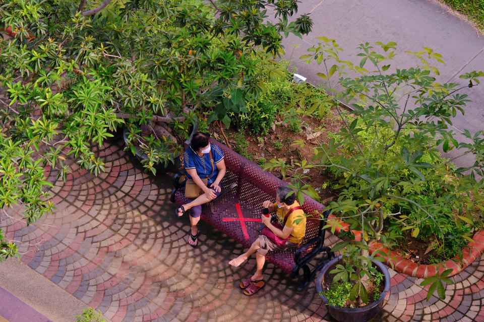 Singapore Sep2020 Two women in neighbourhood wearing protective face masks, observing social distancing in public. Public bench taped with a cross; covid-19 coronavirus lockdown