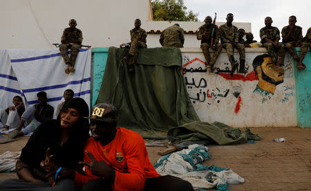 Sudanese demonstrators protest outside the Defence Ministry as soldiers sit on a wall of a military compound in Khartoum, Sudan April 14, 2019. REUTERS/Umit Bektas