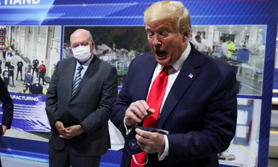 Donald Trump holds a facemask he said he wore during his Ford plant visit.