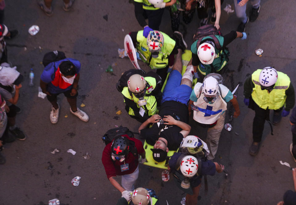 FILE - In this Nov. 8, 2019 file photo, an injured man is carried to safety by volunteers during anti-government protests in the Plaza Italia in Santiago, Chile. In less than a month, more than 230 Chileans have lost sight in one eye, mostly due to the impact of pellets fired by the police during clashes with protesters demanding greater equality and improved social services. (AP Photo/Esteban Felix, File)