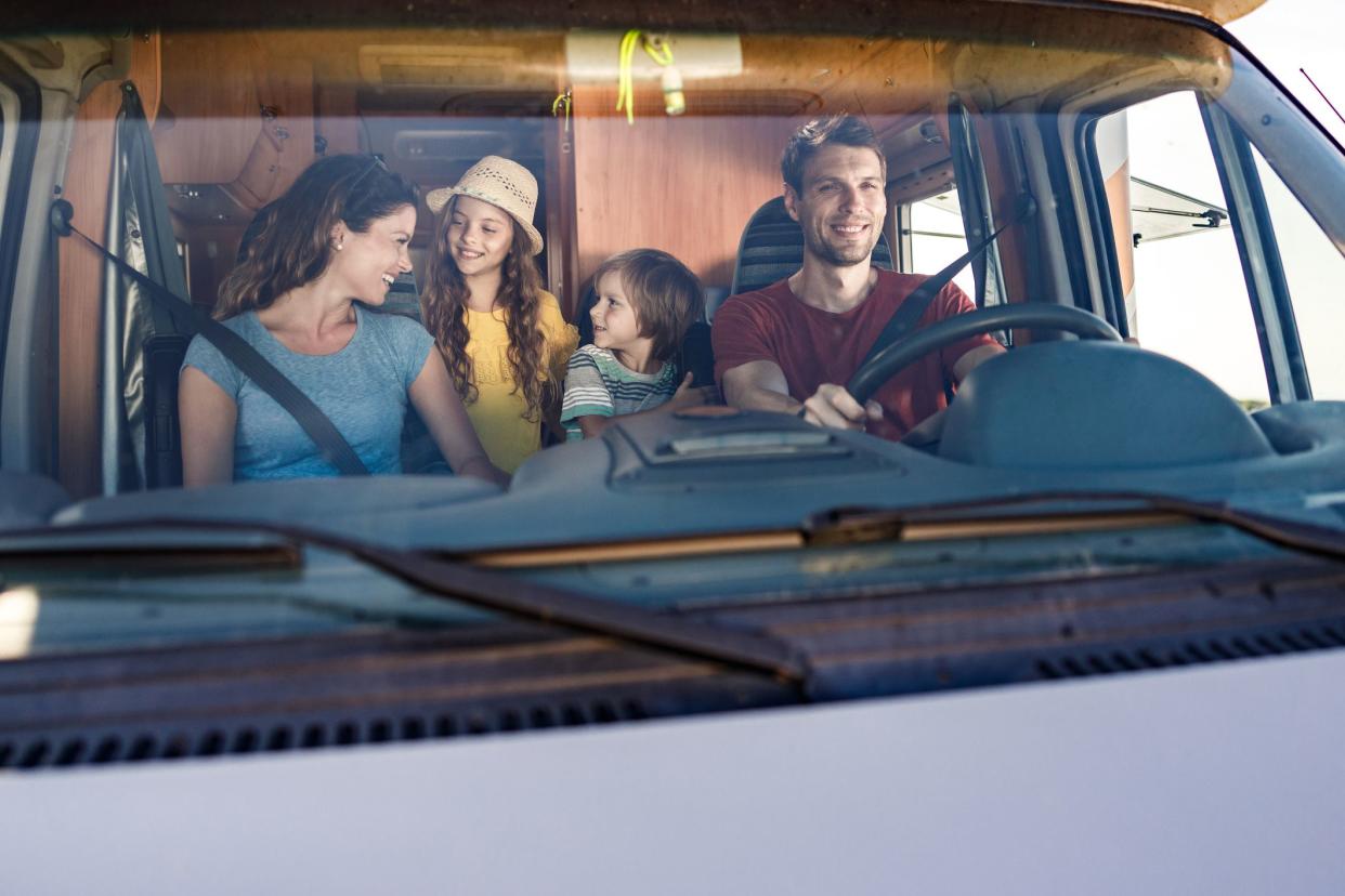 Happy family communicating while going on their vacation with a camp trailer. The view is through windshield.