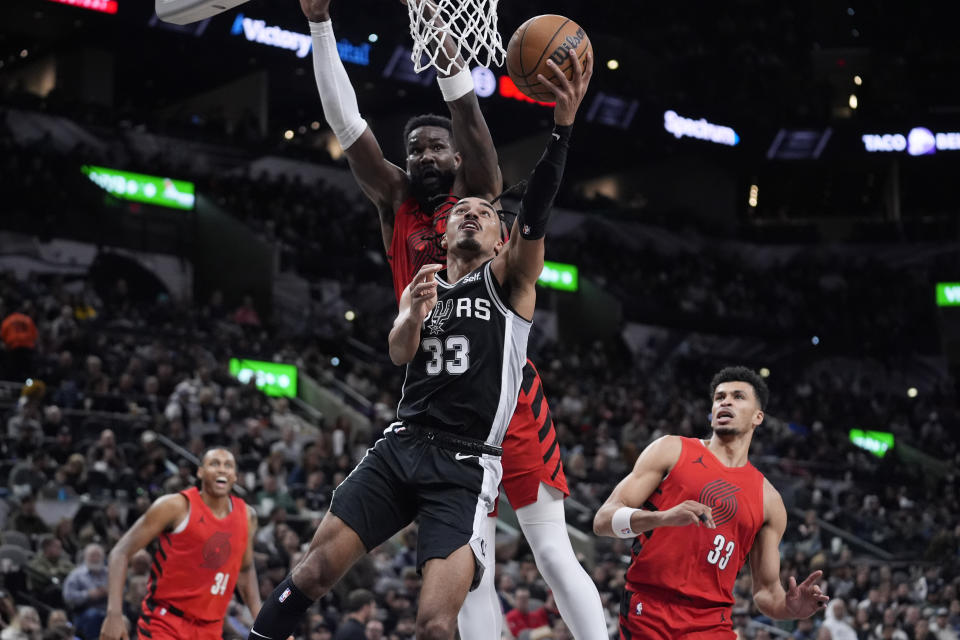 San Antonio Spurs guard Tre Jones (33) scores against Portland Trail Blazers center Deandre Ayton, center rear, during the second half of an NBA basketball game in San Antonio, Friday, Jan. 26, 2024. (AP Photo/Eric Gay)