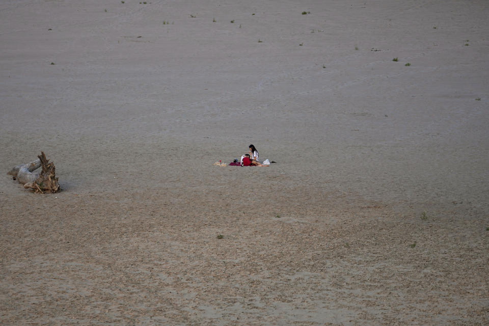 A young couple relax in Boretto, Italy, on the bed of the Po river, Tuesday, June 14, 2022. The drying up of the river is jeopardizing drinking water in Italy's densely populated and highly industrialized districts and threatening irrigation in the most intensively farmed part of the country. (AP Photo/Luca Bruno)