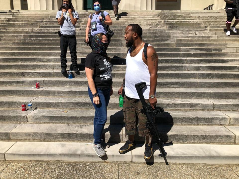 Frank Wilson, holding a semiautomatic rifle, talks with fellow Black Lives Matter protester Tiffany Ray in Louisville.