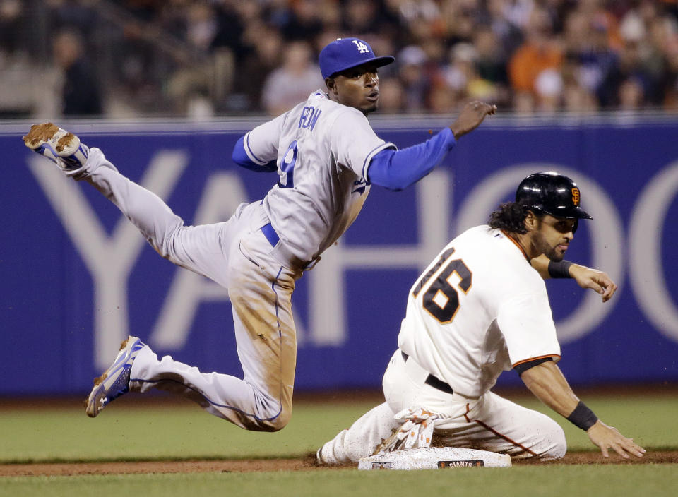 Los Angeles Dodgers second baseman Dee Gordon, left, looks to first after forcing out San Francisco Giants' Angel Pagan (16) at second base on a ground ball from Hunter Pence during the third inning of a baseball game on Wednesday, April 16, 2014, in San Francisco. Pence was safe at first. (AP Photo/Marcio Jose Sanchez)