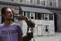 Lucio Ferrara, who works in bird control for the municipality in Piazza del Plebiscito, holds his eagle named, Iena, as he walks in the yard of the Royal palace where the house of U.S. civil rights campaigner Rosa Parks was rebuilt for public display by artist Ryan Mendoza, in Naples, Italy, Tuesday, Sept. 15, 2020. The rundown, paint-chipped Detroit house where Parks took refuge after her famous bus boycott is going on display in a setting that couldn't be more incongruous: the imposing central courtyard of the 18th century Royal Palace. (AP Photo/Gregorio Borgia)