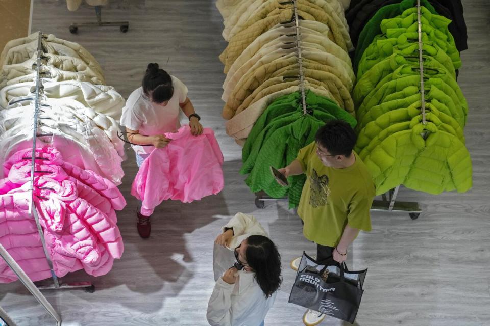 A woman tries out a fall outfit at a booth at a shopping mall in Beijing.