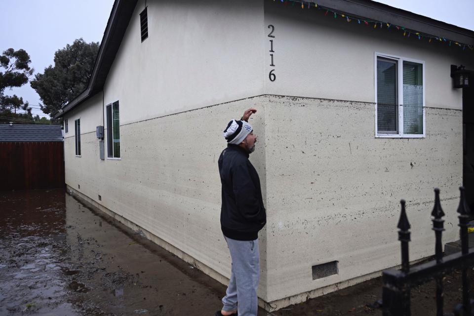 Juan Gonzales gestures to the waterline of a flooded home during a rain storm Monday, Jan. 22, 2024, in San Diego.