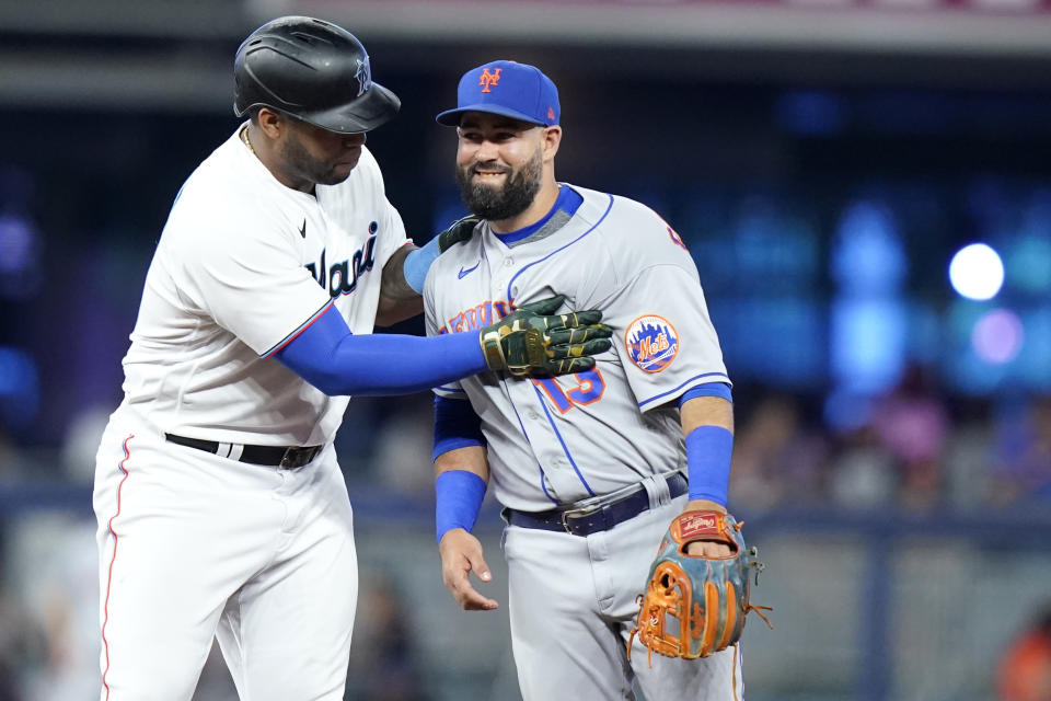 Miami Marlins' Jesus Aguilar, left, jokes with New York Mets second baseman Luis Guillorme (13) after advancing from first to second on a wild pitch thrown by New York Mets starting pitcher David Peterson during the first inning of a baseball game, Sunday, June 26, 2022, in Miami. (AP Photo/Lynne Sladky)