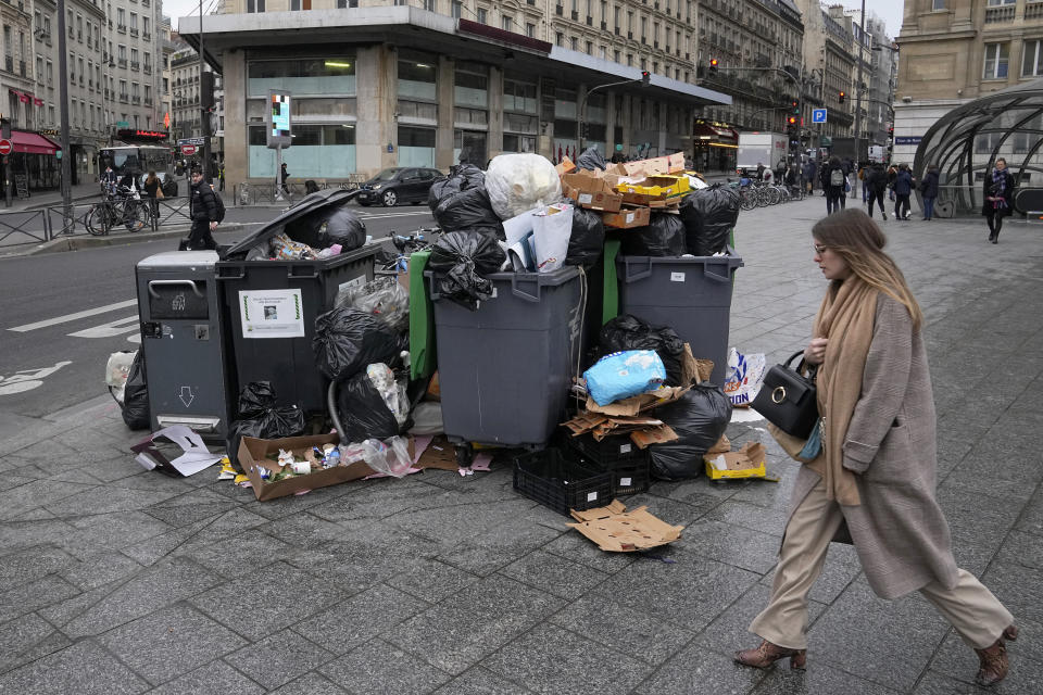 Una mujer pasa por delante de una pila de contedores de basura llenos, el 7 de marzo de 2023, en París. (AP Foto/Michel Euler)