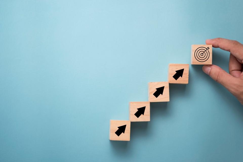 A hand arranging wooden blocks in a pattern indicating growth.