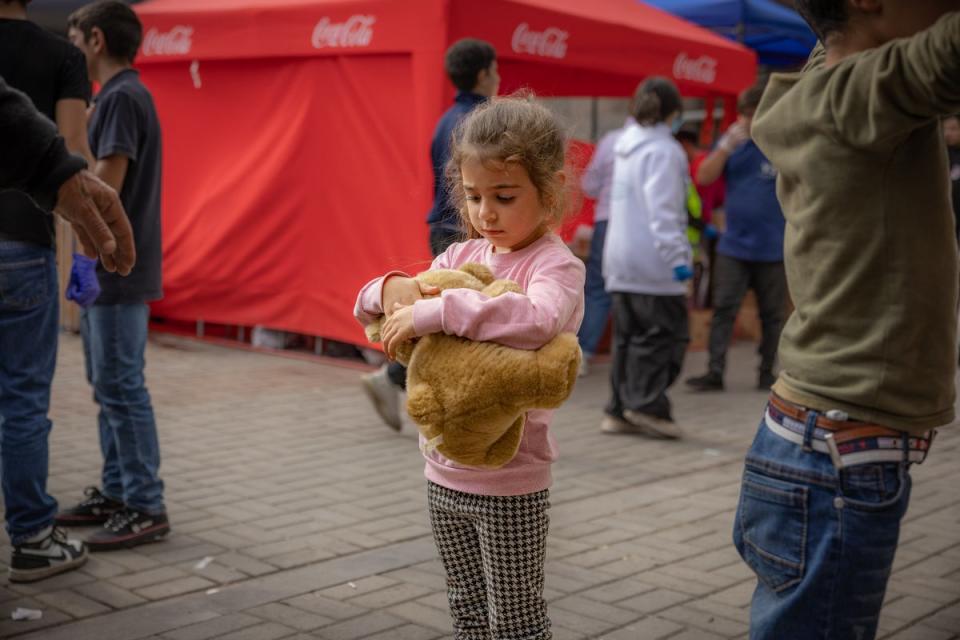 A refugee cuddles a teddy after arriving from a two day journey to Goris in Armenia (Bel Trew)