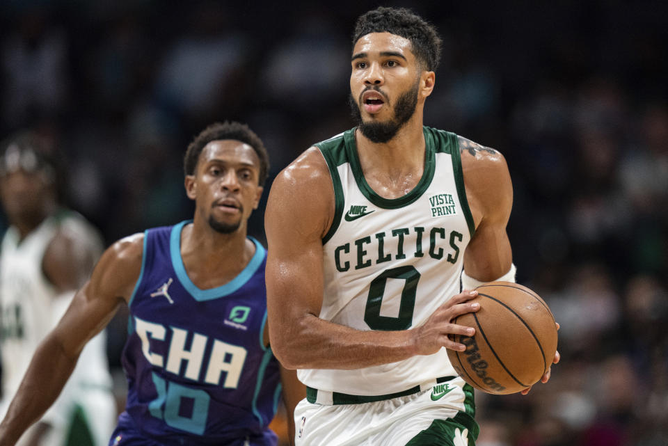 Boston Celtics forward Jayson Tatum (0) brings the ball upcourt while chased by Charlotte Hornets guard Ish Smith (10) during the first half of an NBA basketball game in Charlotte, N.C., Monday, Oct. 25, 2021. (AP Photo/Jacob Kupferman)