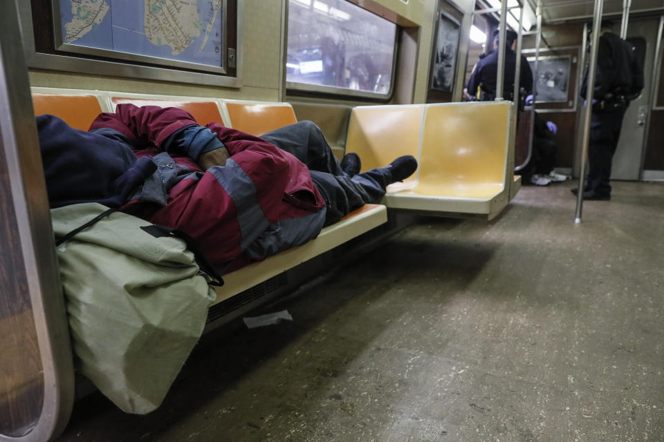 NYPD officers wake up sleeping passengers and direct them to the exits at the 207th Street A-train station, Thursday, April 30, 2020, during the coronavirus pandemic, in the Manhattan borough of New York. (AP Photo/John Minchillo)