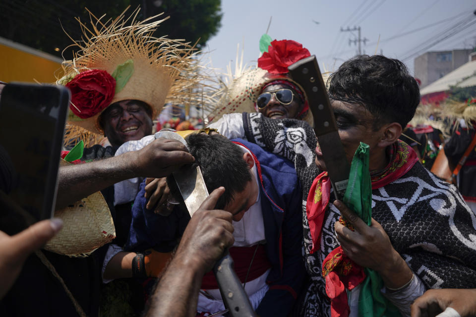 People dressed as Zacapoaxtla Indigenous fighters use a machete to cut the hair of a person dressed as a French soldier, as they re-enact The Battle of Puebla as part of Cinco de Mayo celebrations in the Peñon de los Baños neighborhood of Mexico City, Thursday, May 5, 2022. Cinco de Mayo commemorates the victory of an ill-equipped Mexican army over French troops in Puebla on May 5, 1862. (AP Photo/Eduardo Verdugo)