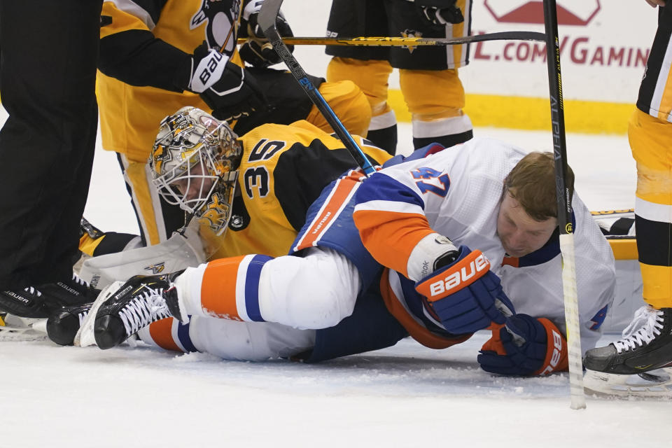Pittsburgh Penguins goaltender Tristan Jarry (35) covers the puck after a play as New York Islanders' Leo Komarov, rolls on the ice after losing his helmet during the second period of an NHL hockey game Saturday, March 27, 2021, in Pittsburgh. (AP Photo/Keith Srakocic)
